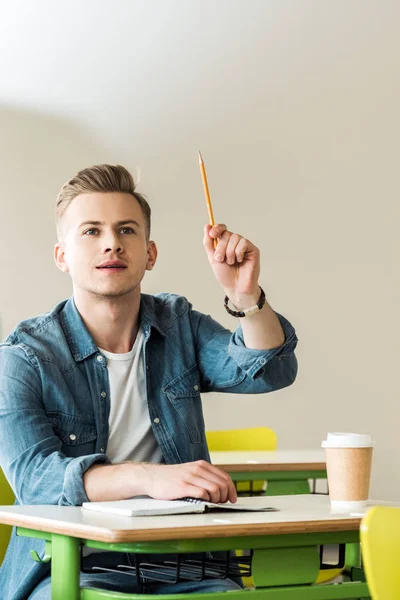 Estudiante Camisa Mezclilla Sentado Escritorio Levantando Mano Con Lápiz — Foto de Stock