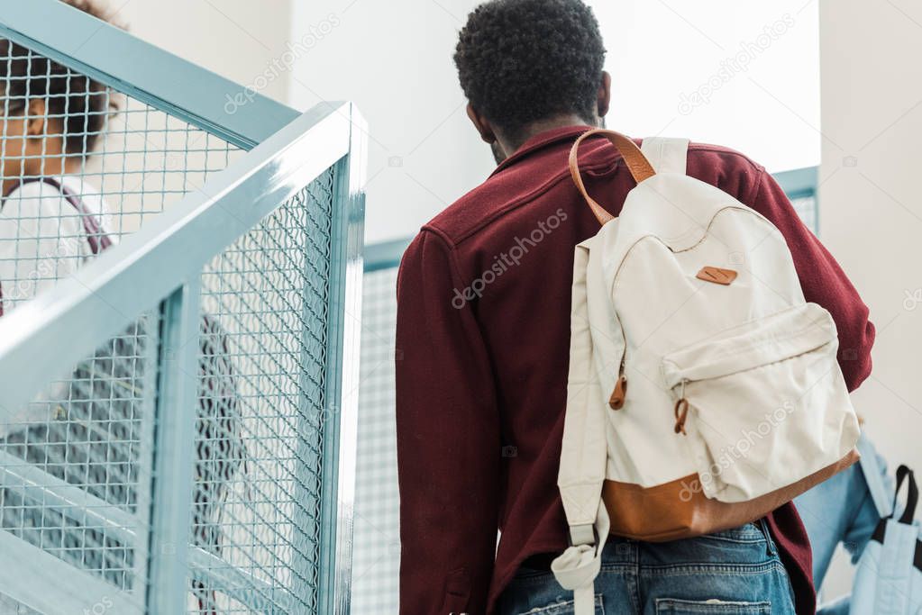 cropped view of students with backpacks on stairs in university