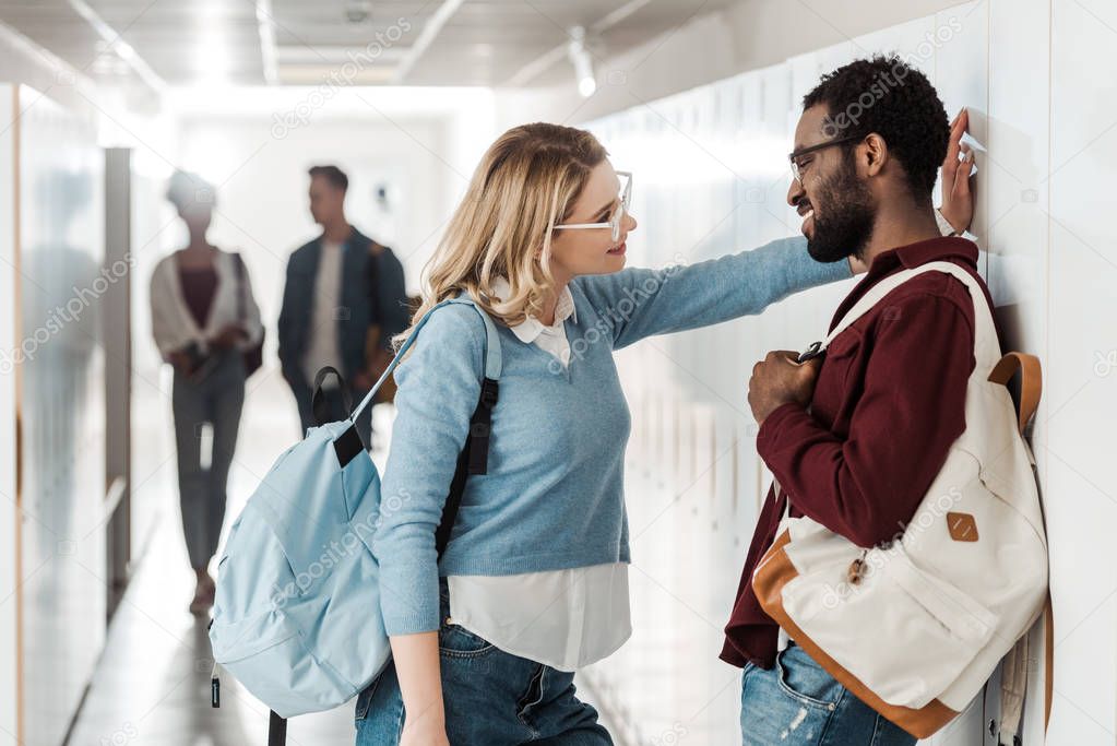 smiling multiethnic students standing in corridor in university