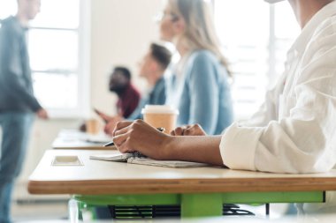 üniversitede kalem ve not defteri ile öğrencinin kırpılmış görünümü