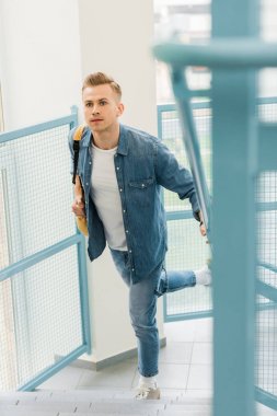 running student in denim shirt with backpack in college clipart