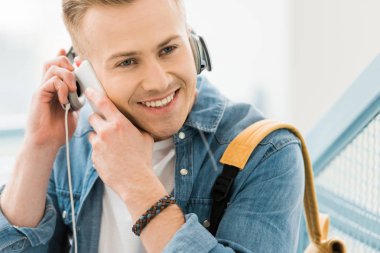 üniversitede akıllı telefonda konuşan kulaklık gülümseyen öğrenci