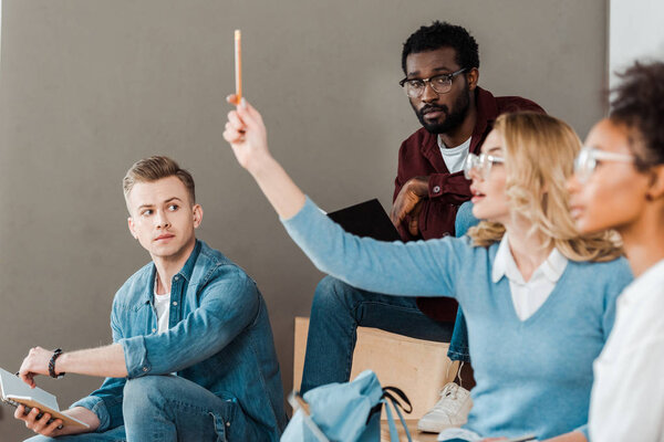 multicultural students in glasses with notebooks in lecture hall