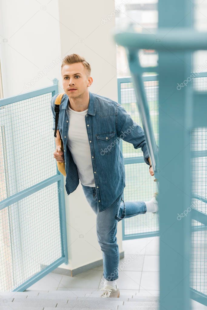 running student in denim shirt with backpack in college