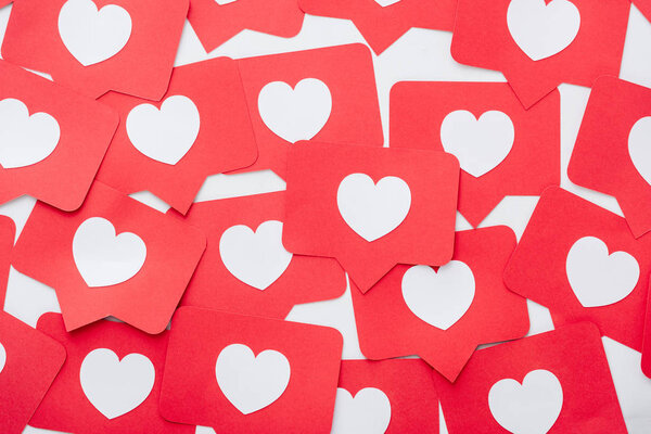top view of red paper cut cards with hearts symbols on white surface