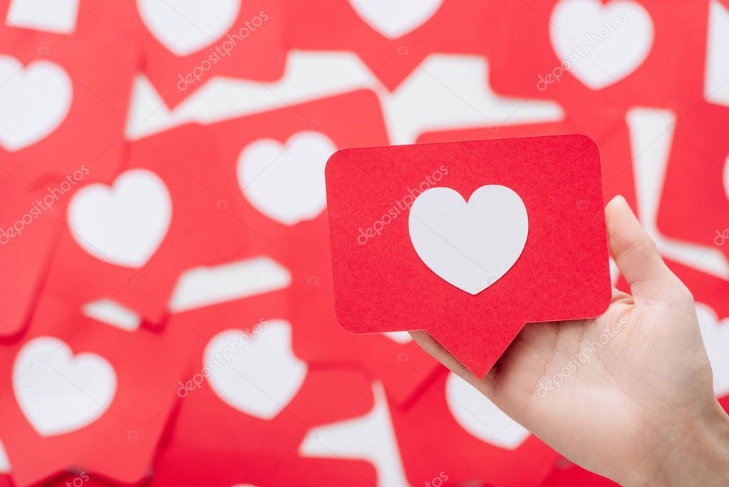 cropped view of female hand with red paper cut card with heart symbol 
