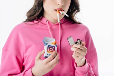 beyaz izole instagram logosu ile sigara paketi tutan ağzında sigara ile genç kız kırpılmış görünümü