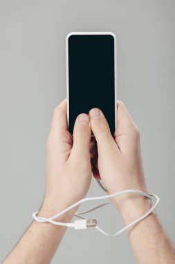 gri izole boş ekran ile akıllı telefon tutan ellerde usb kablosu ile adam kırpılmış