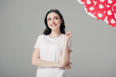 fikir işareti gösteren güzel genç kız ve gri izole kalpleri sembolü ile kırmızı kağıt kesme kartları yakın bakarak