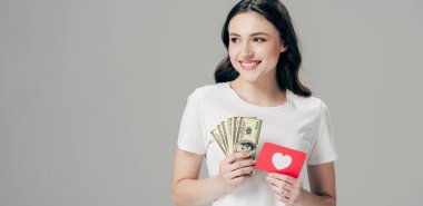 gri izole kalp sembolü ile dolar banknotlar ve kırmızı kağıt kesme kartı tutan mutlu kız panoramik çekim