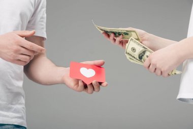 gri izole kalp sembolü ile kırmızı kağıt kesme kartı ile adama dolar banknotlar veren kadın kırpılmış görünümü