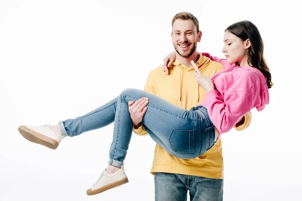 Fidanzato Sorridente Guardando Fotocamera Mentre Tiene Ragazza Utilizzando Smartphone Isolato — Foto Stock