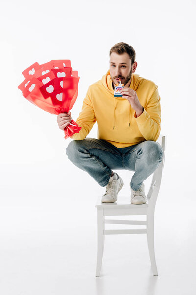 smiling man with bouquet of red paper cut cards with hearts symbols holding cigarette pack with instagram logo on white background