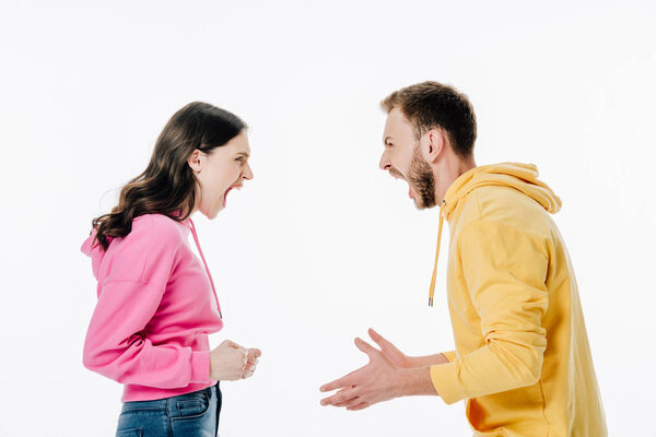 side view of young couple in hoodies quarreling isolated on white