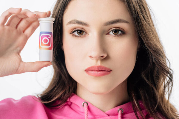 beautiful girl holding container with instagram logo and looking at camera isolated on white