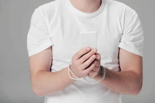灰色で隔離されたスマートフォンを使用して手の周りにUsbケーブルを持つ若者の部分的なビュー — ストック写真