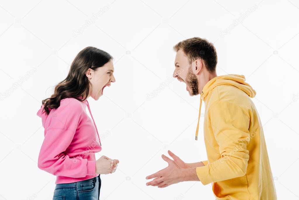 side view of young couple in hoodies quarreling isolated on white