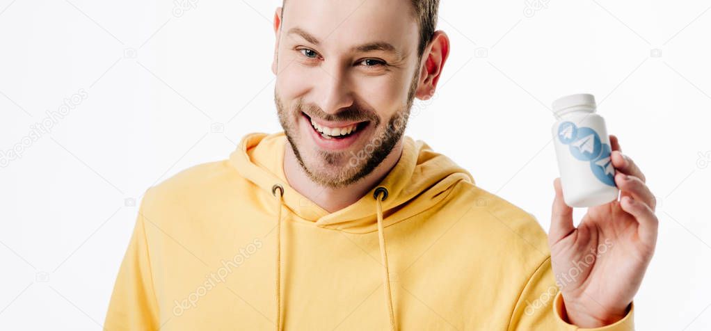 Panoramic shot of cheerful young man holding container with telegram logo isolated on white