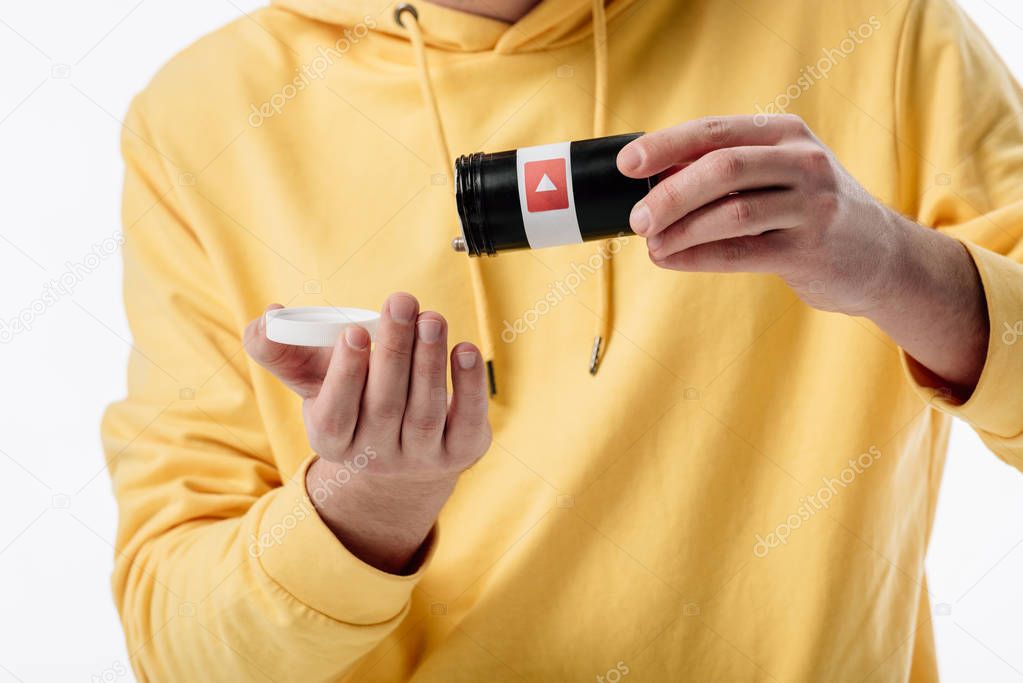 Partial view of young man getting pills from container with youtube logo isolated on white