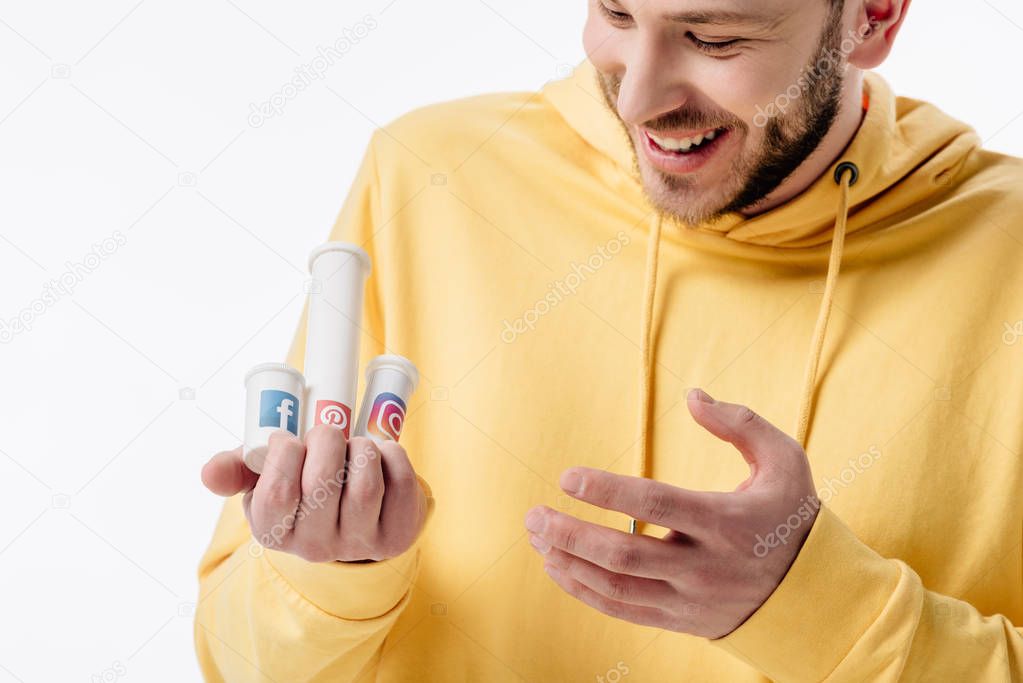 Handsome excited young man holding containers with social media logos isolated on white