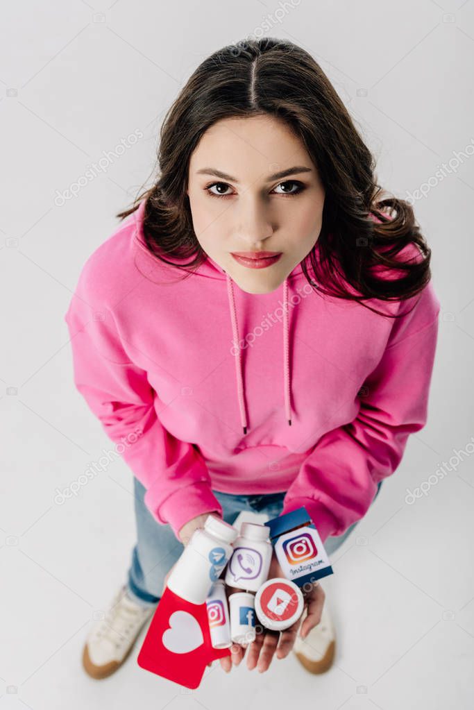 Overhead view of girl holding containers with social media logos and red paper cut card with heart symbol isolated on grey