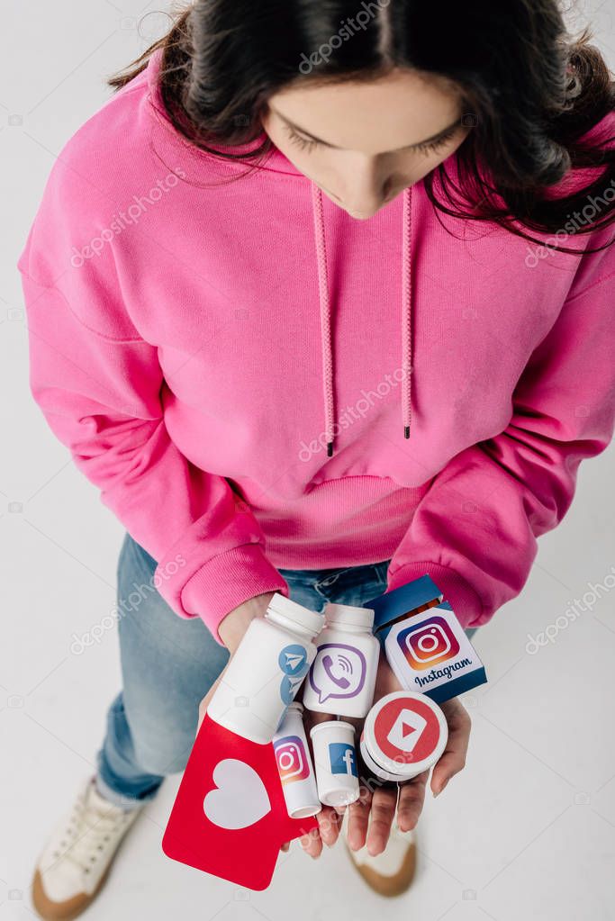 Overhead view of girl holding containers with social media logos and red paper cut card with heart symbol on grey background