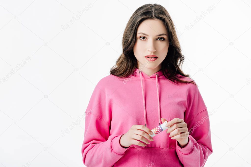 Thoughtful beautiful young woman holding container with instagram logo isolated on white