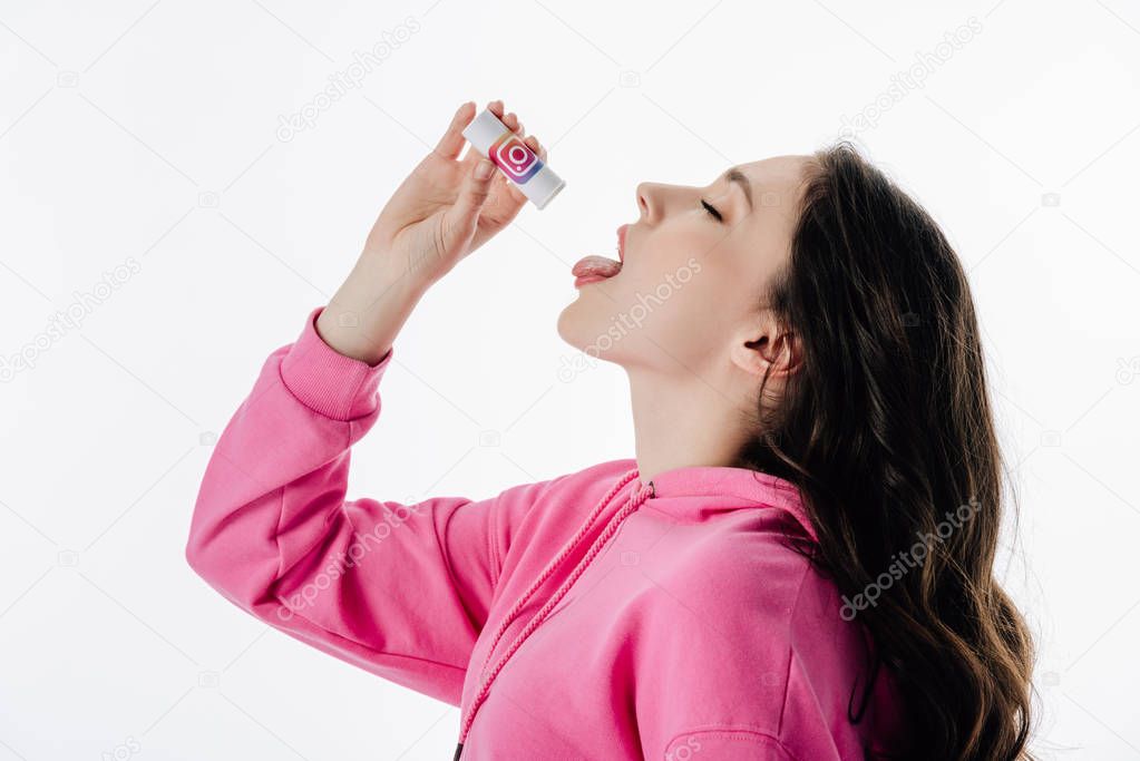 Pretty girl with closed eyes imitating using pills from container with instagram logo isolated on white