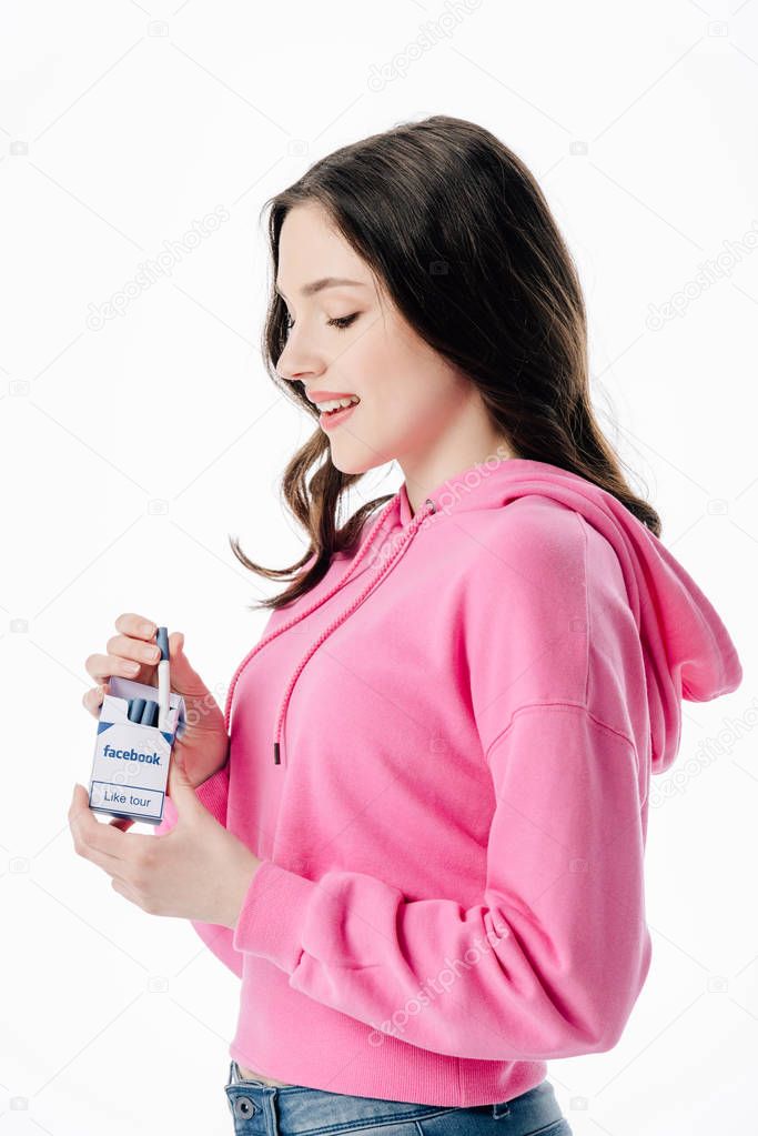 Attractive smiling girl holding cigarette pack with facebook logo isolated on white