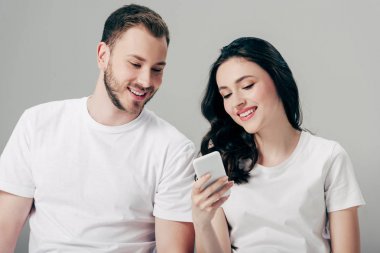 gri izole akıllı telefon kullanarak beyaz t-shirt neşeli genç adam ve kadın