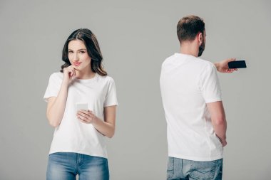 gri izole akıllı telefon ile selfie çekerken genç adamın yanında duran beyaz t-shirt gülümseyen çekici kız