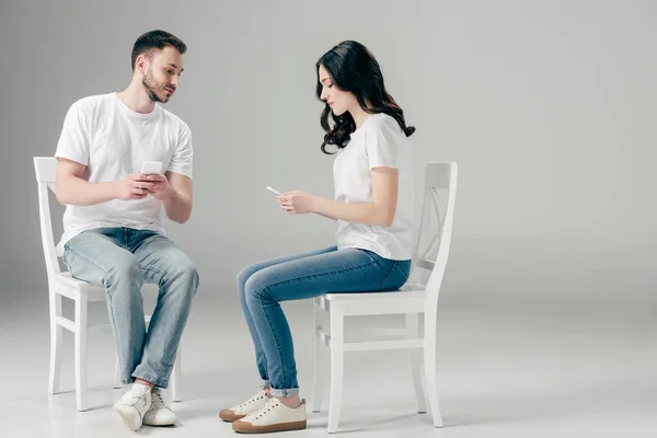 Hombre Mujer Concentrados Camisetas Blancas Vaqueros Azules Sentados Sillas Usando — Foto de Stock