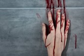 krvácející ruka a krevní tisk na šedé stěně