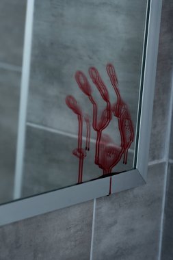 selective focus of bloody handprint on mirror in bathroom