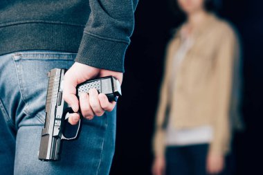 cropped view of criminal hiding gun while standing near woman on black clipart