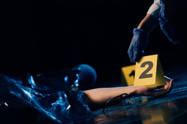 partial view of covered corpse and investigator with evidence marker at crime scene clipart