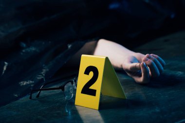 cropped view of covered dead body on floor near glasses and evidence marker clipart