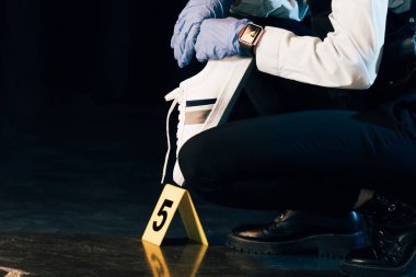 partial view of investigator in rubber gloves holding evidence at crime scene clipart