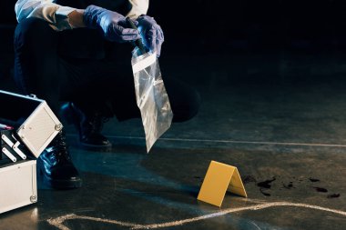 cropped view of investigator in uniform with evidence at crime scene clipart