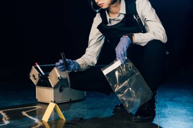 olay yerinde bıçak ve ziploc çanta tutan araştırmacı kırpılmış görünümü