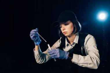 investigator in rubber gloves holding swab and test tube at crime scene clipart