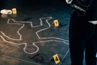 cropped view of investigator standing near chalk outline and evidence markers at crime scene clipart