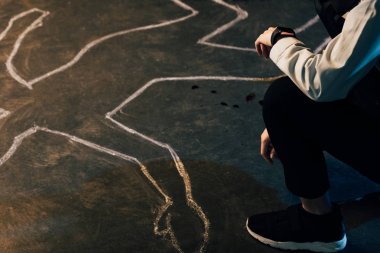 partial view of investigator sitting near chalk outline at crime scene clipart