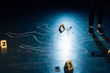 partial view of investigator standing near chalk outline and evidence markers clipart