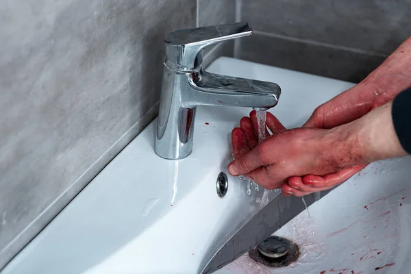 partial view of man washing bleeding hands in sink