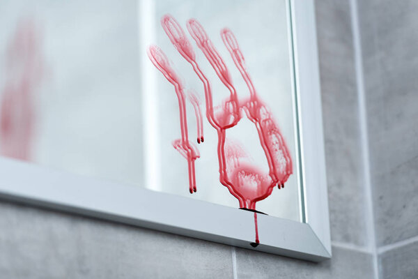 selective focus of bloody handprint on mirror in bathroom