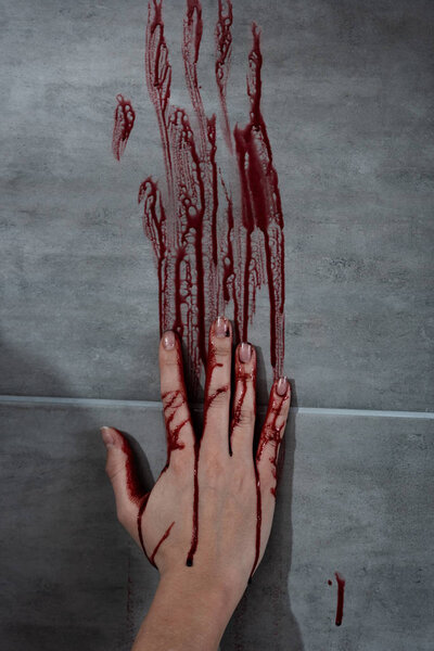 кровоточащий отпечаток руки и крови на серой стене
