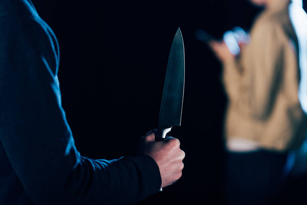 cropped view of killer holding knife near woman isolated on black