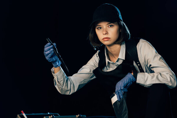 investigator in uniform holding knife and ziploc bag at crime scene
