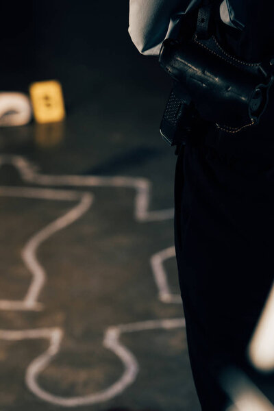 cropped view of investigator with gun at crime scene